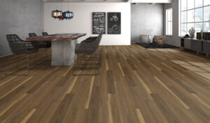 Spacious dining area with rustic wooden flooring, a large table with a concrete base, modern pendant lights, and large windows for natural light.