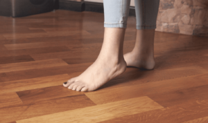 Close-up of bare feet on polished wooden flooring with a natural finish, showing comfort and warmth.