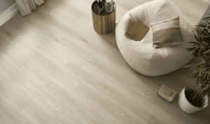 Minimalist room with light wooden flooring, a cozy white beanbag chair, striped pillow, side table with decor, and a potted plant.