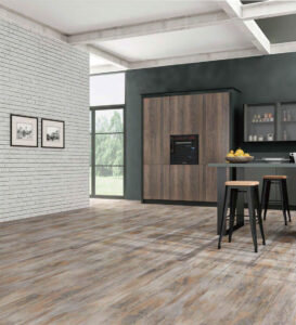 Industrial-style kitchen with distressed wood flooring, dark cabinets, exposed beams, white brick wall, and a breakfast bar with stools.