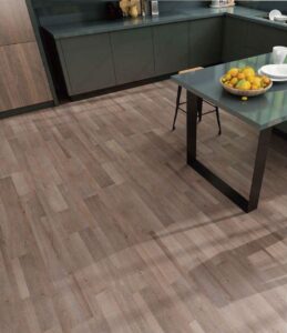 Modern kitchen with matte dark cabinets, natural wood flooring, and a sleek dining table topped with a bowl of fresh lemons.