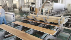 Flooring planks on an assembly line in a factory, with workers and machinery in the background.