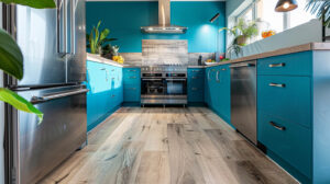 Modern kitchen with teal cabinets, stainless steel appliances, and light wood flooring, featuring natural light and indoor plants.