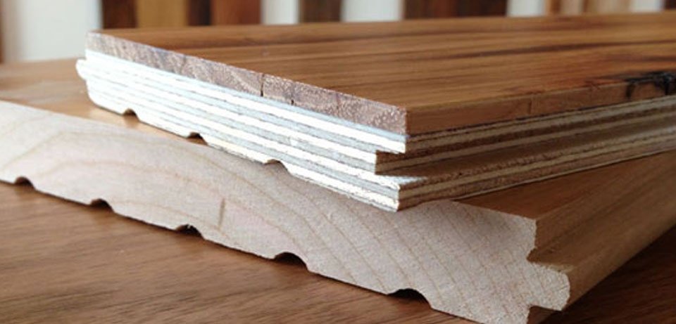 Close-up of engineered wood flooring cross-section showing multiple plywood layers beneath a hardwood veneer.