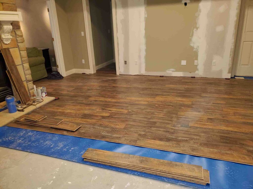Dark brown SPC flooring installation over blue vapor barrier
