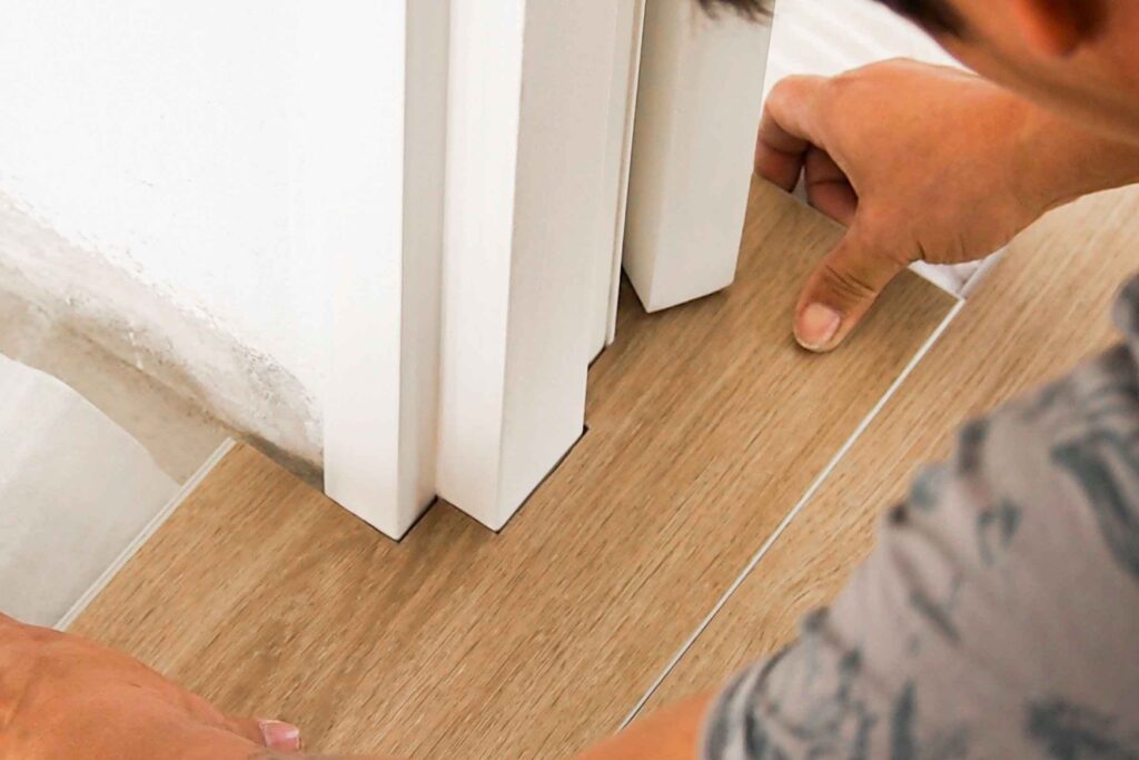 Installing SPC vinyl flooring under door frame with precision.