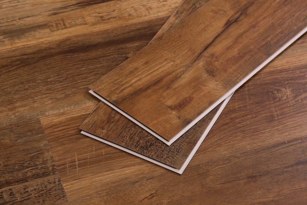 Close-up of three vinyl plank flooring pieces laid over dark wood surface with natural grain and texture.